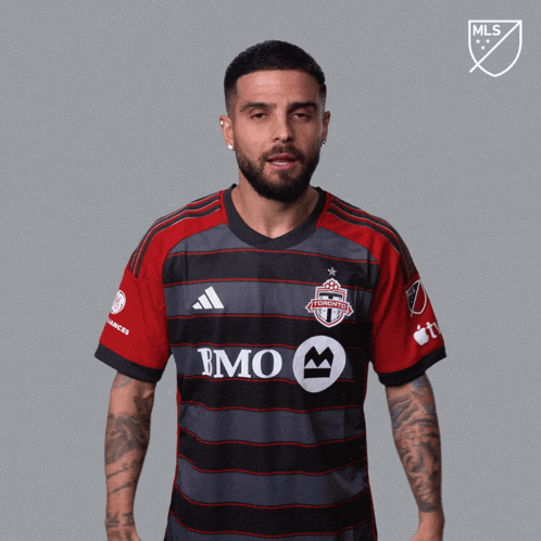 a man wearing a toronto fc jersey holds his fists up in the air