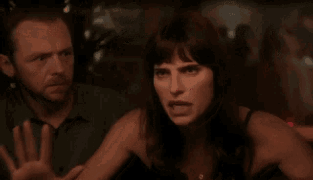 a man and a woman are standing next to each other in a dark room . the woman is making a funny face .