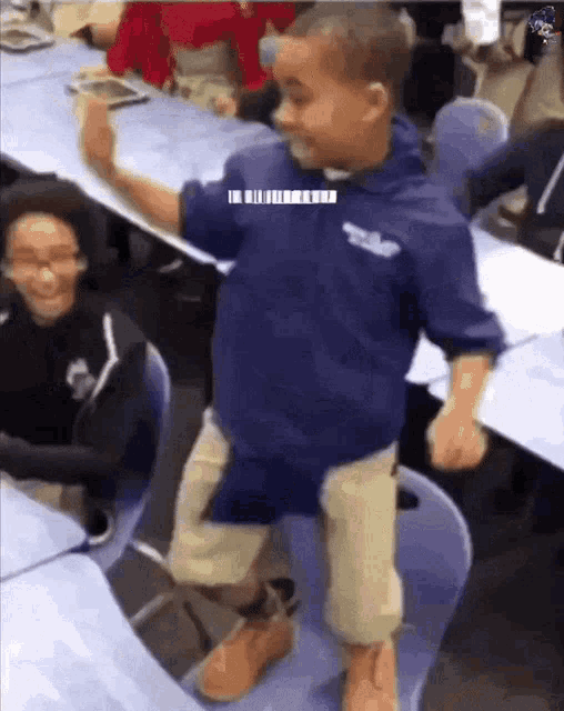 a boy in a blue shirt is dancing in a classroom with other children