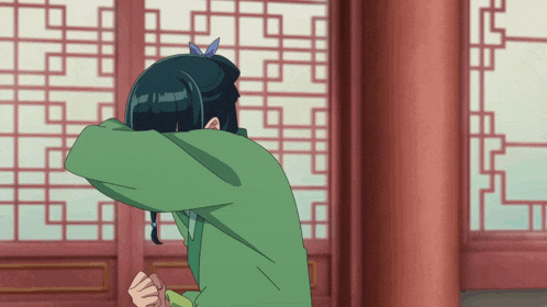 a girl in a green shirt is covering her face with her hands