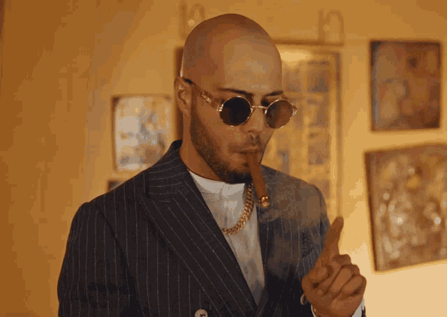 a man in a suit smoking a cigar and wearing round sunglasses