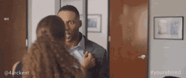 a man and a woman are standing next to each other in a hallway .