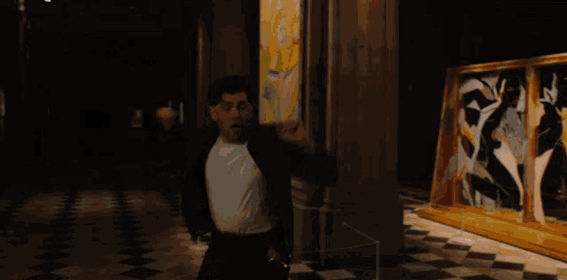 a man in a white shirt is running in a hallway