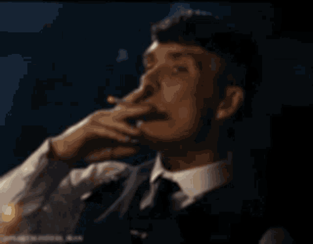 a man in a suit is smoking a cigarette