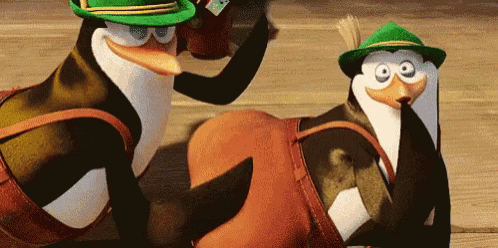 two penguins wearing green hats are laying on a wooden surface