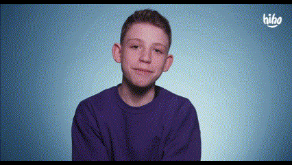 a young boy wearing a purple shirt is smiling and looking at the camera .