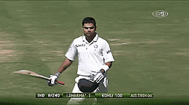 a man in a white shirt is holding a bat in front of a tv screen that says ind 8/240