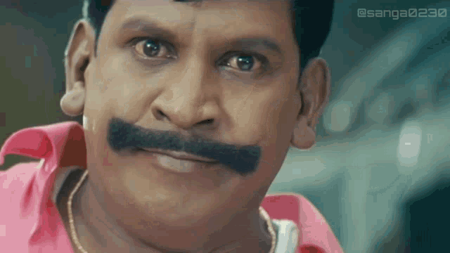 a man with a mustache is wearing a pink shirt and a gold chain around his neck