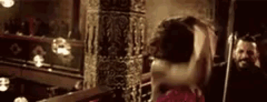 a woman in a red dress is dancing in front of a mirror in a room .