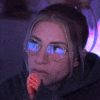 a woman wearing glasses is holding a piece of food in her mouth