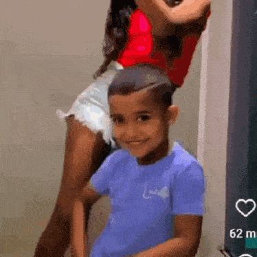 a woman in shorts is standing next to a young boy in a blue shirt .