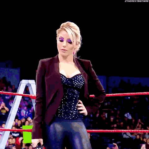 a woman is standing in a wrestling ring with a ladder in the background