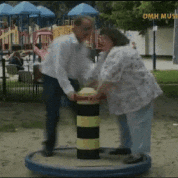 a man and a woman are playing on a merry go round in a park with omn music written on the bottom