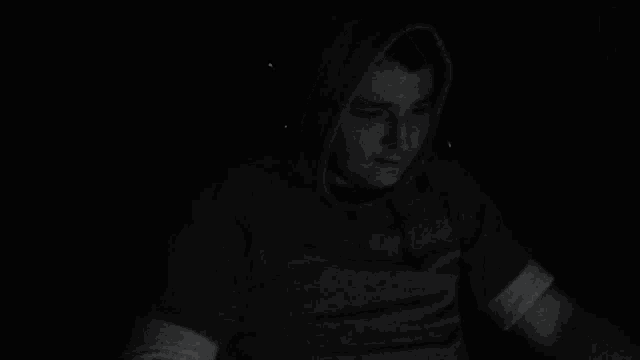 a man in a hoodie is giving a peace sign in the dark .