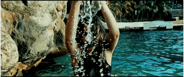 a woman is splashing water over her head in a swimming pool