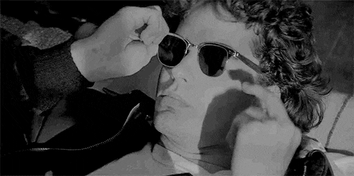 a man wearing sunglasses is laying down on a bed .