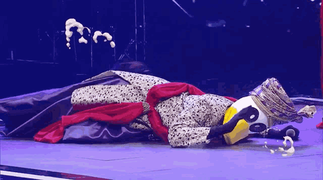 a person in a penguin costume is laying on the ground