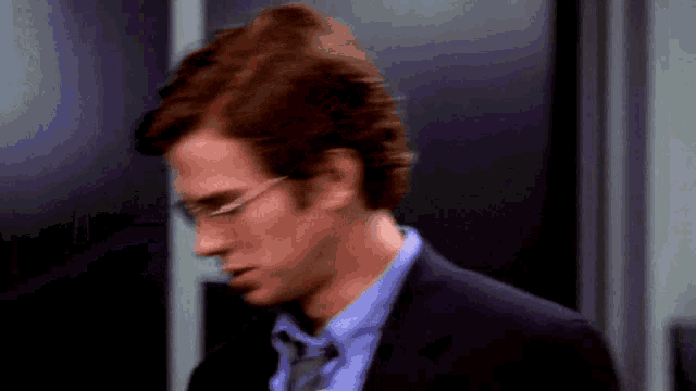a man wearing glasses and a suit looks down