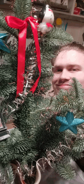 a man is standing in front of a christmas tree with decorations
