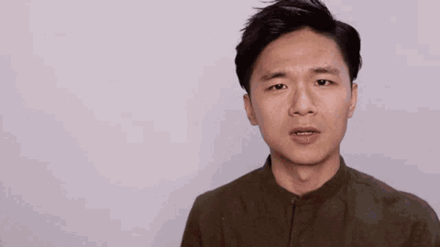 a man is making a face in front of a wall with chinese writing on it