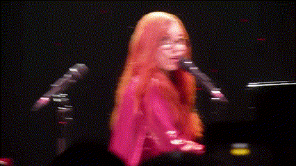 a woman singing into a microphone with her eyes closed