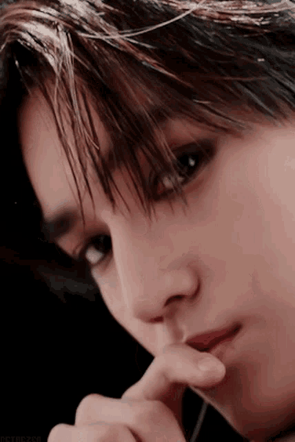 a close up of a man 's face with his finger on his lips