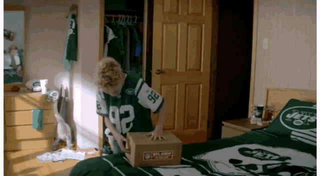 a boy in a jets jersey holds a box
