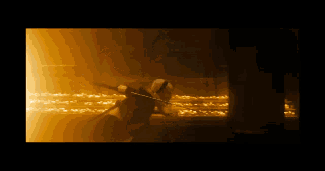 a person holding a sword in a dark room with a yellow light behind them