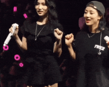 two women are dancing on a stage while holding microphones .