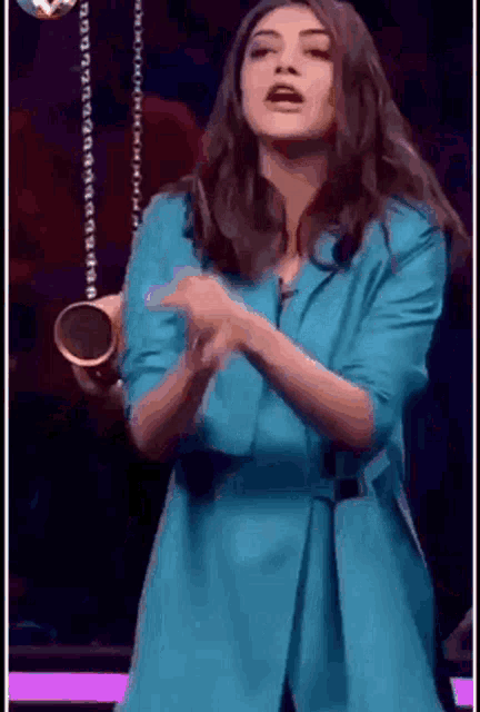 a woman in a blue jacket is dancing and holding a microphone