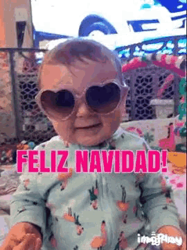 a baby wearing heart shaped sunglasses and a flamingo pajamas is sitting on a bed .