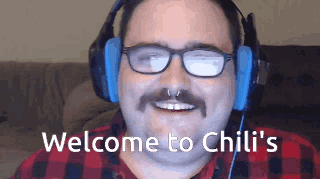 a man with glasses and headphones is smiling and says welcome to chili 's .