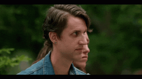 a man in a denim jacket is drinking from a paper cup