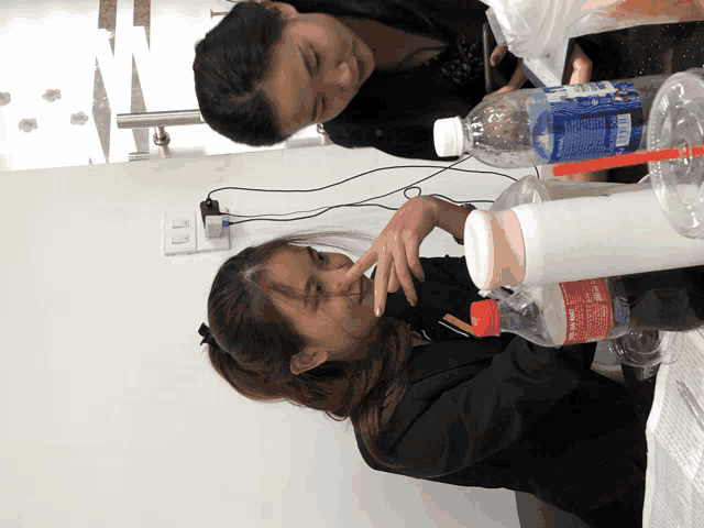 two women sitting at a table with a coca cola bottle