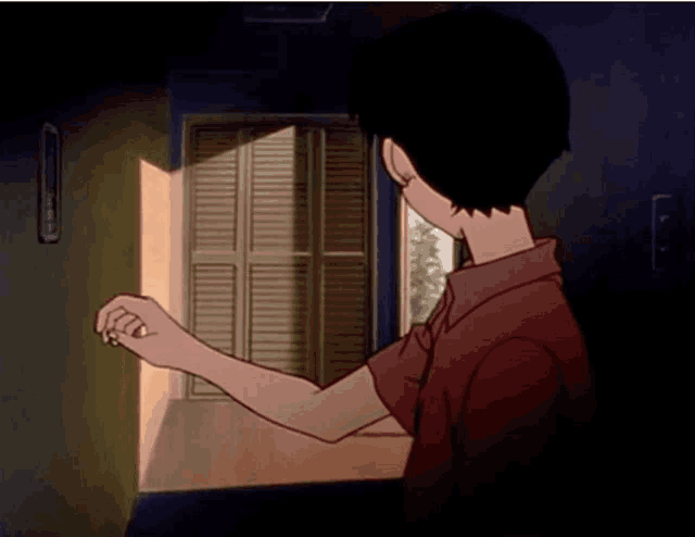 a boy in a red shirt is looking out of a window