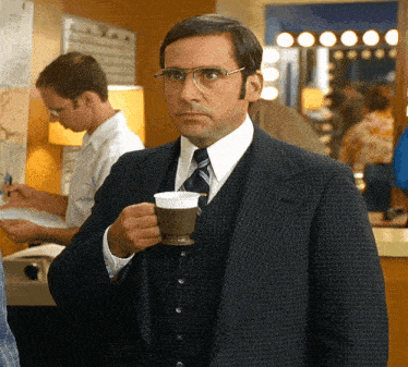 a man in a suit and tie is drinking from a cup