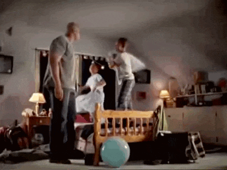 a man and two children are playing with pillows in a room .