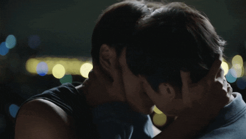 two men are kissing in a dark room