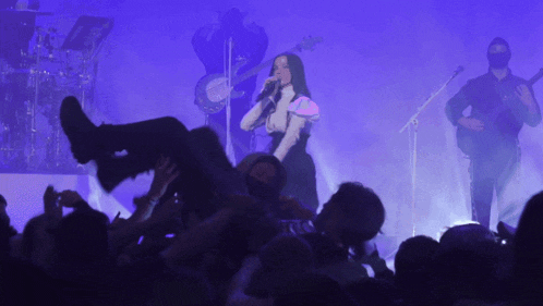 a woman singing into a microphone while a man plays a banjo in the background