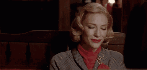 a woman in a grey suit and red turtleneck is sitting on a bench .