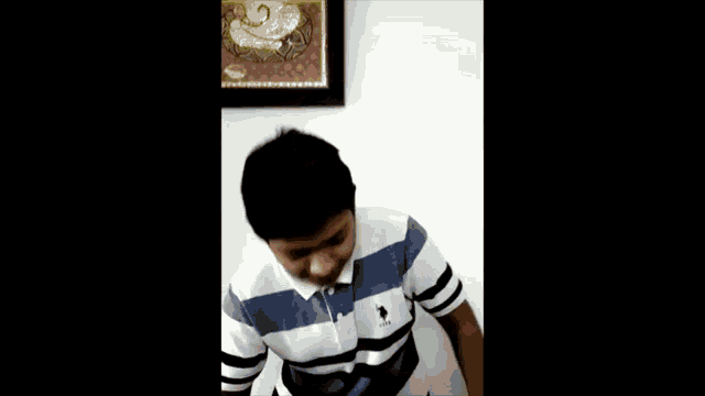 a young man in a striped shirt is eating a bowl of food