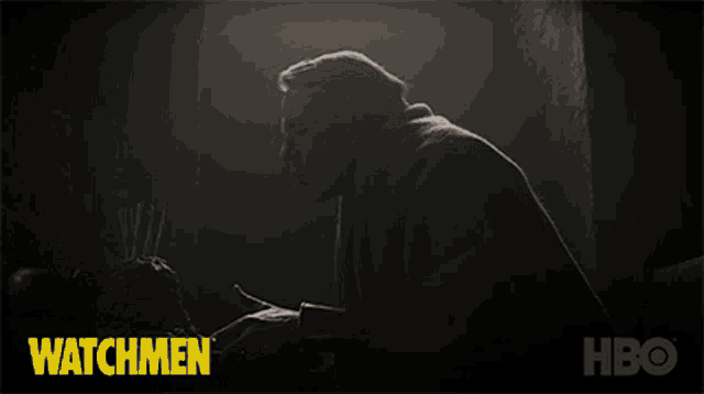 a man is sitting in a dark room with the words watchmen behind him