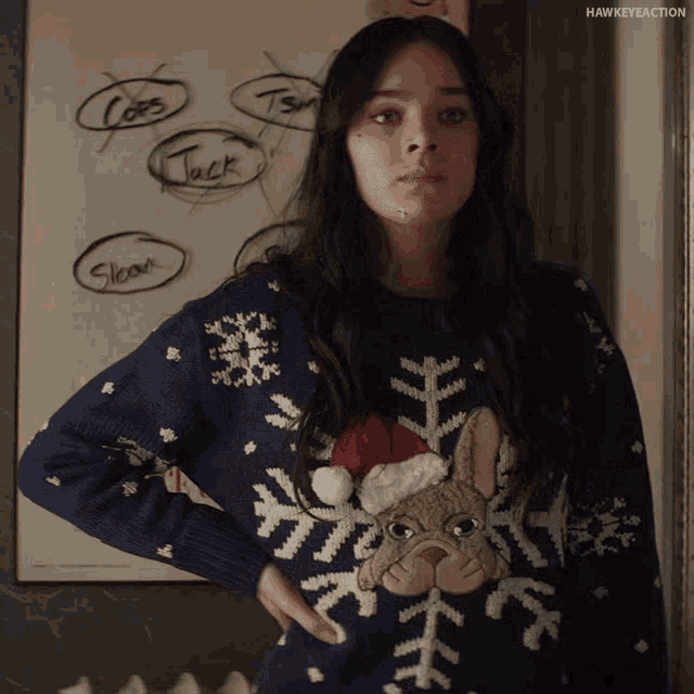 a woman wearing a blue sweater with a bulldog on it and a santa hat