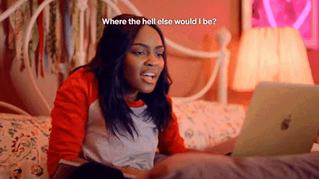 a woman sitting on a bed looking at a laptop with the words " where the hell else would i be " written above her