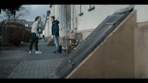 a man and a boy standing on a sidewalk talking