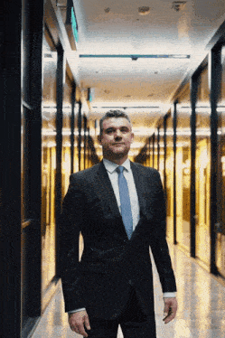 a man in a suit and tie is standing in a dark hallway
