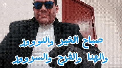 a man wearing sunglasses and a jacket is standing in front of a door in a room .