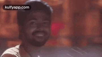a man with a beard is smiling and looking at the camera in a blurry photo .