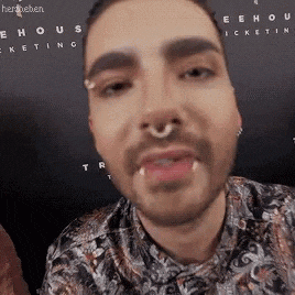 a man with a beard and a nose ring is making a face .
