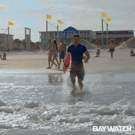 a man is running out of the water holding a life preserver .